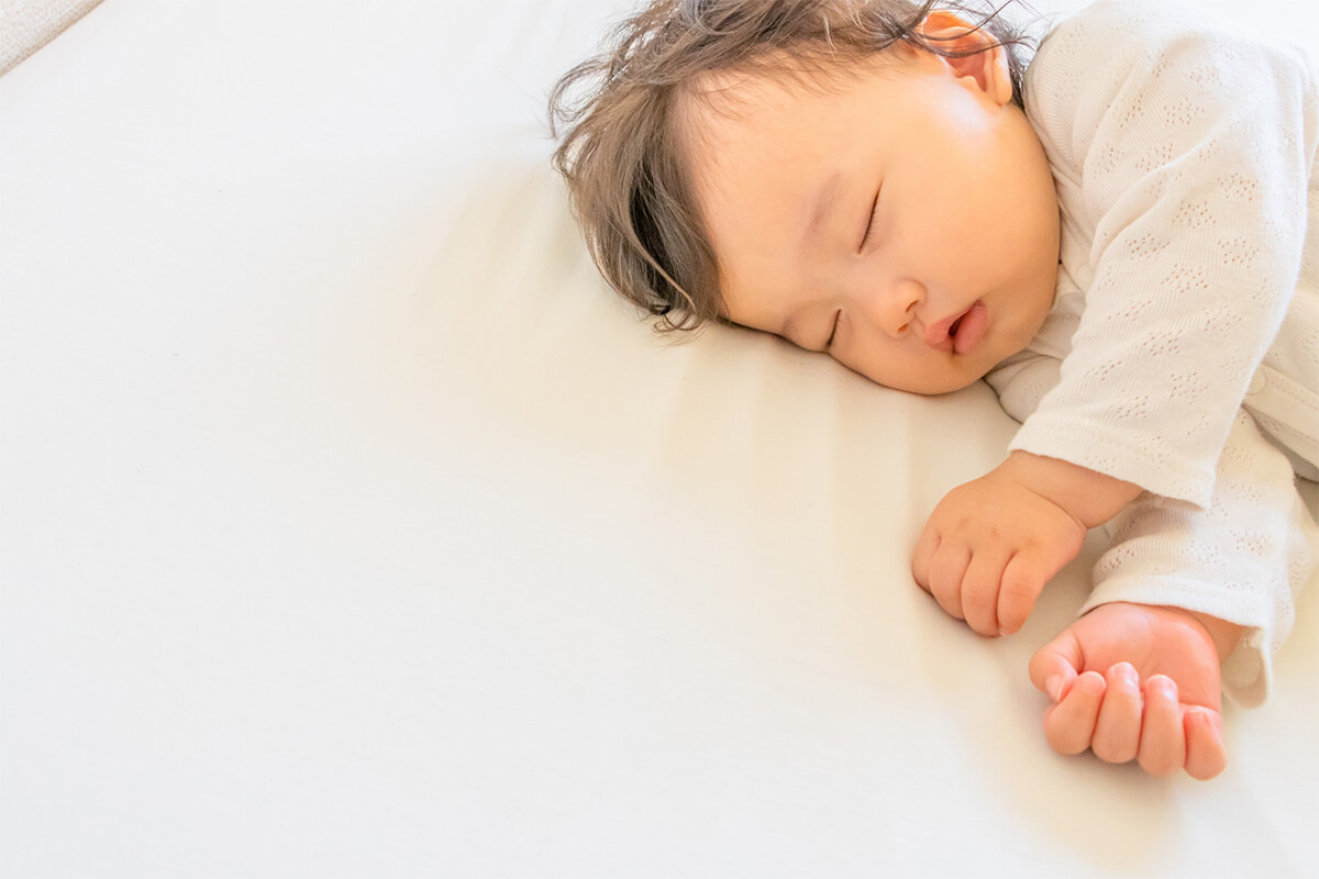 白いベッドに寝ている赤ちゃん。