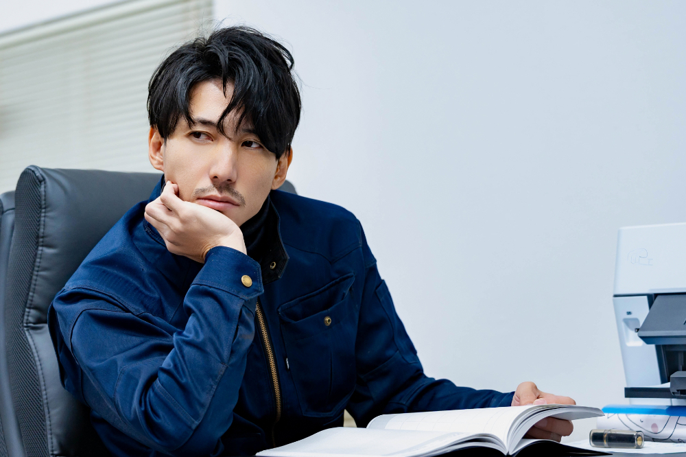 デスクで本を開き、頬杖をつく男性