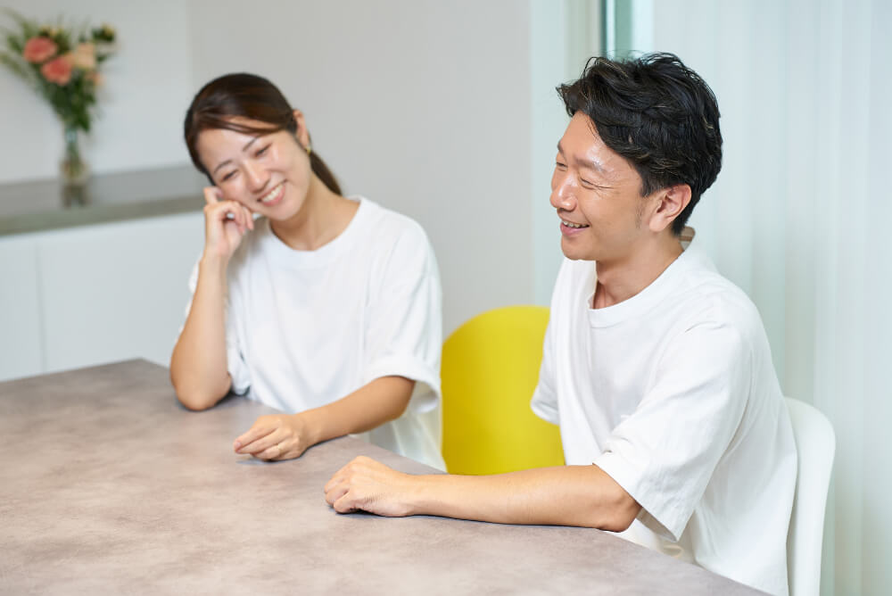 テーブルにつき、談笑する男女。二人とも白いTシャツを着ている