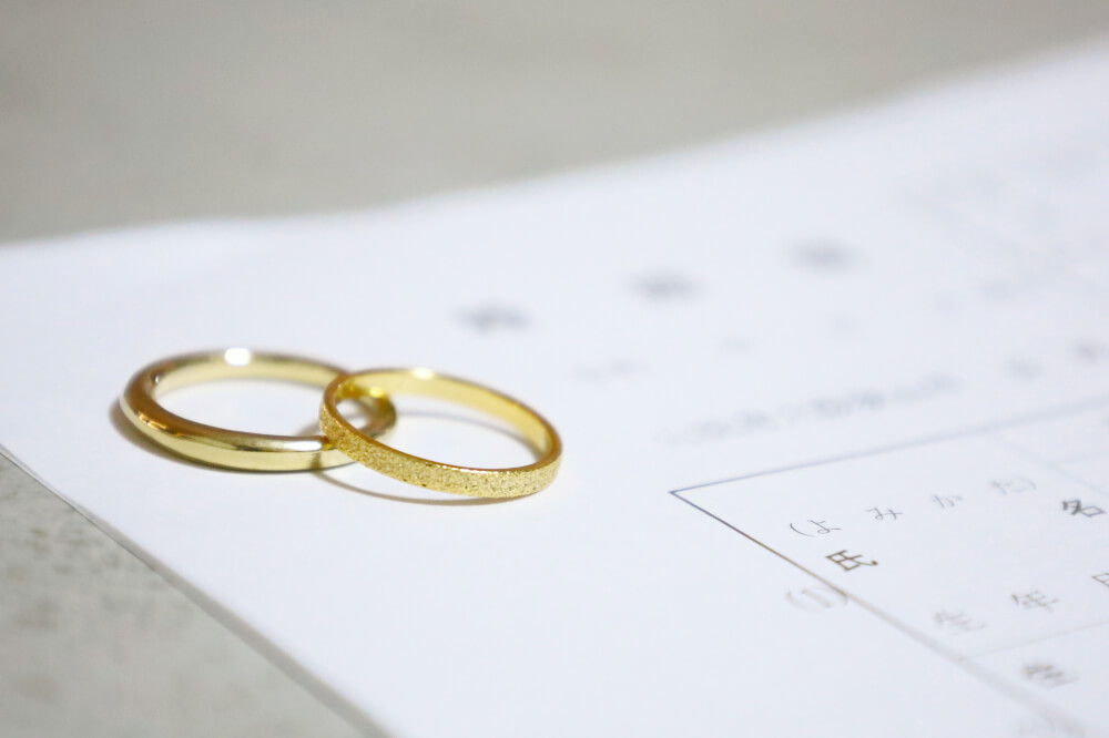 婚姻届けと、その上に置かれたゴールドの結婚指輪